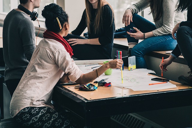 A group of people sitting around a table with paper and pencils,