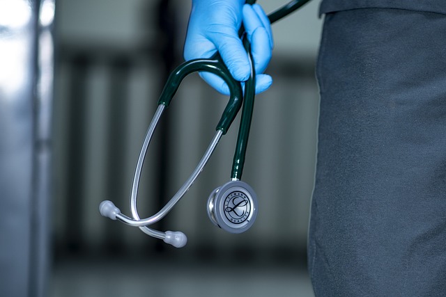 A person in blue gloves holding a stethoscope